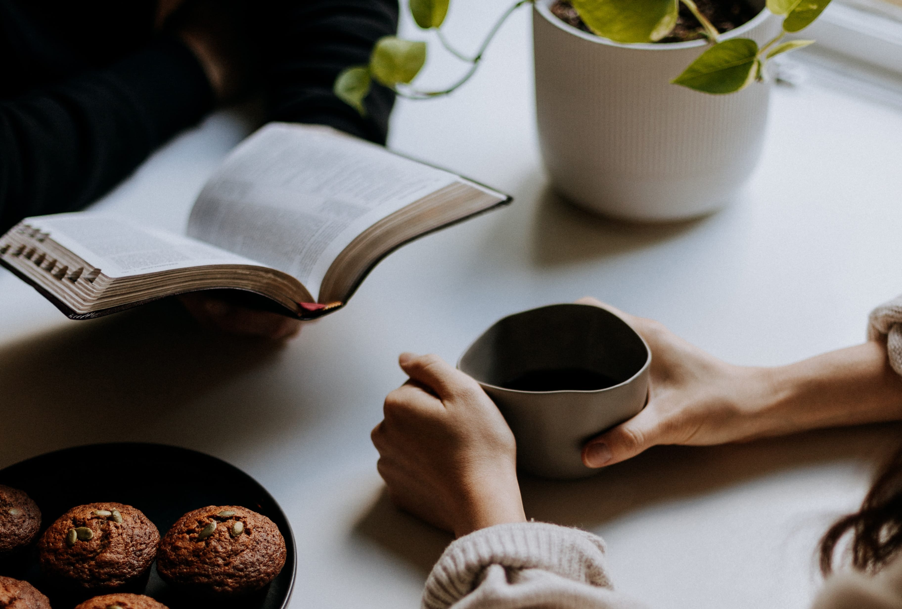 woman holding coffee cup infront of open book